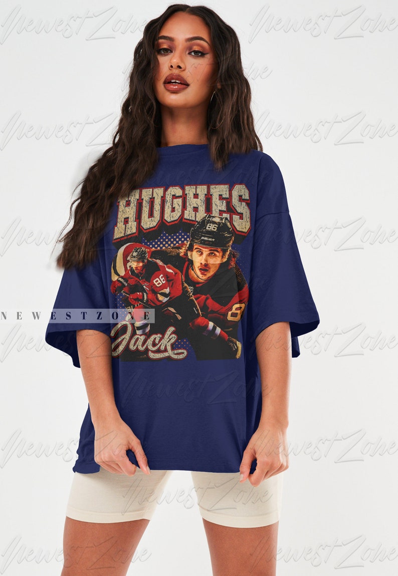 May include: A navy blue oversized t-shirt with a vintage-style graphic of a hockey player wearing a red and white jersey with the number 86. The text "HUGHES" and "Jack" are printed on the shirt.