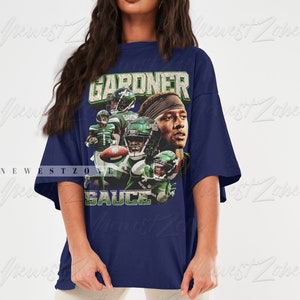 May include: An oversized navy blue t-shirt featuring a graphic print of a football player wearing a green and white jersey. The text "GARDNER" and "SAUCE" are printed on the shirt.