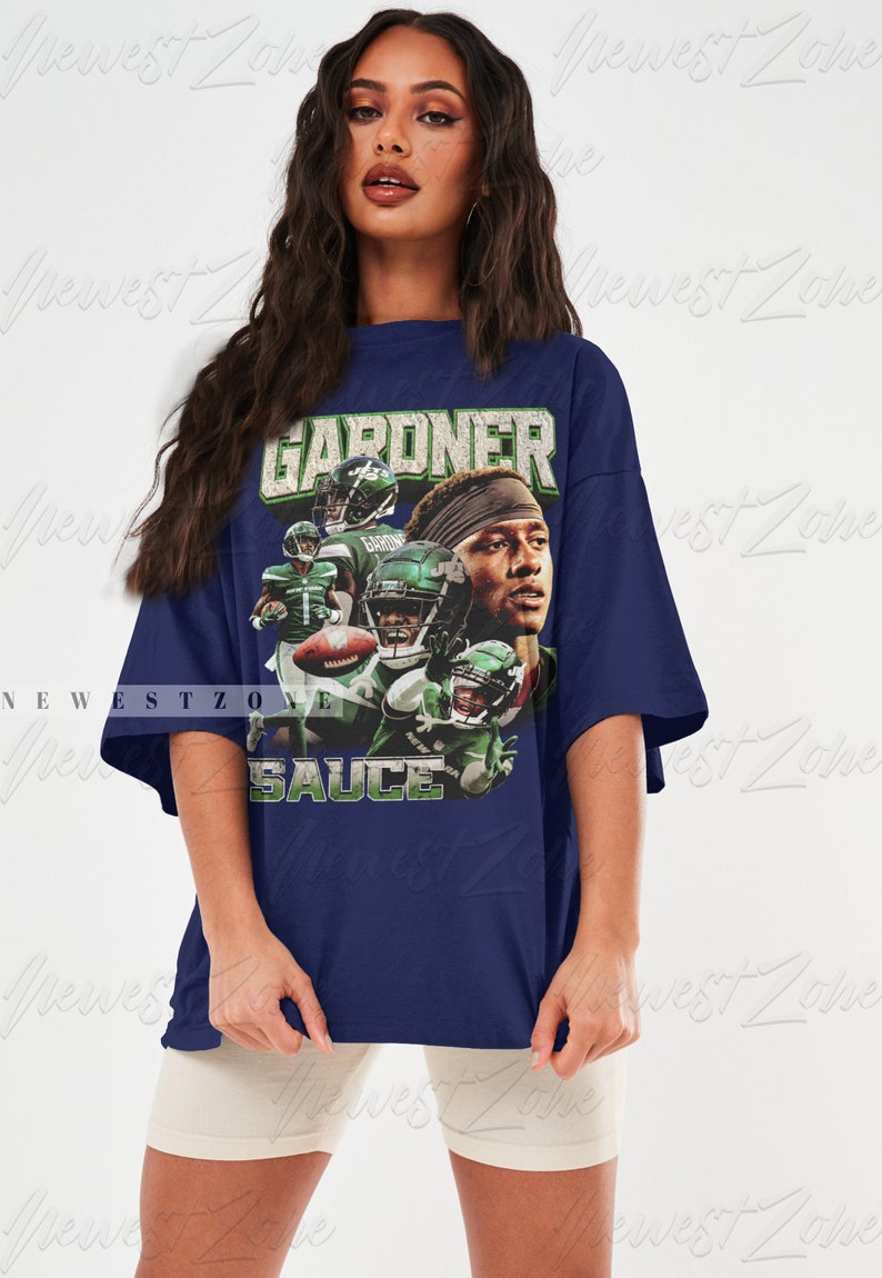 May include: An oversized navy blue t-shirt featuring a graphic print of a football player wearing a green and white jersey. The text "GARDNER" and "SAUCE" are printed on the shirt.