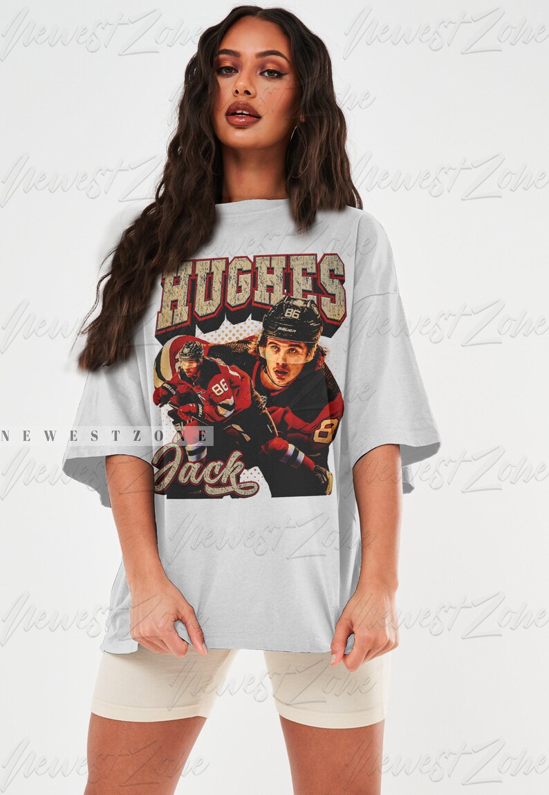 May include: A gray oversized t-shirt with a vintage-style graphic of a hockey player wearing a red and white jersey with the text "HUGHES" and "Jack" on the shirt.