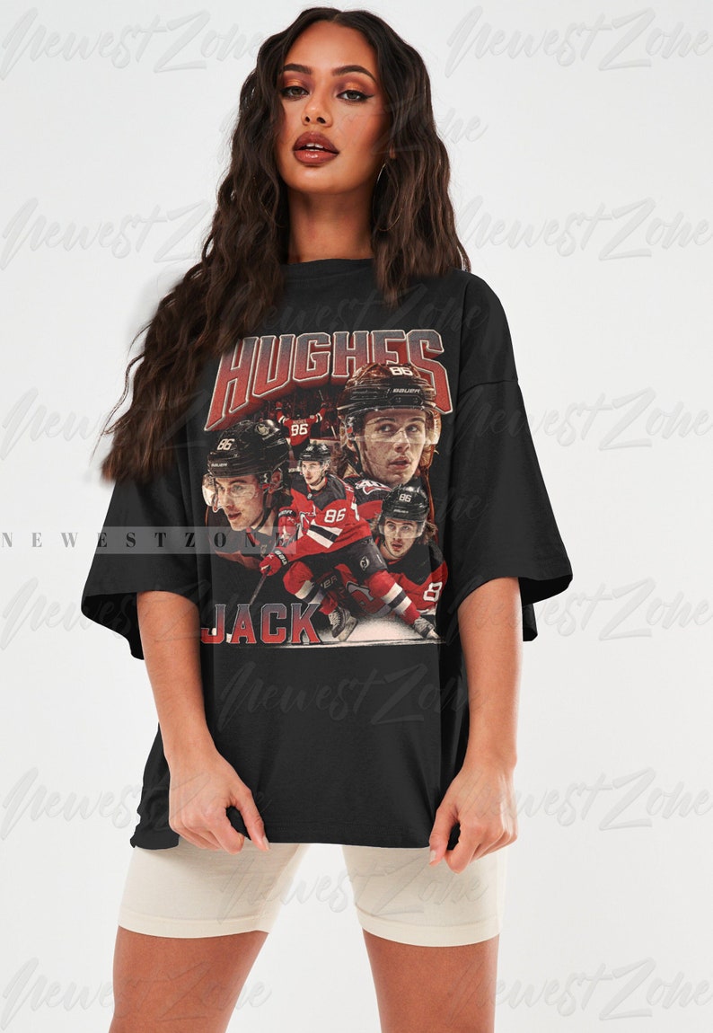 Puede incluir: Camiseta negra de gran tama&ntilde;o con un gr&aacute;fico de estilo vintage del jugador de hockey Jack Hughes. El gr&aacute;fico es un collage de fotos de Hughes en acci&oacute;n, con el texto "HUGHES" y "JACK" impreso en rojo.