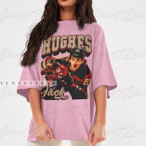 May include: A pink oversized t-shirt with a vintage-style graphic of a hockey player wearing a red and black jersey with the text "HUGHES" and "Jack" on the shirt.