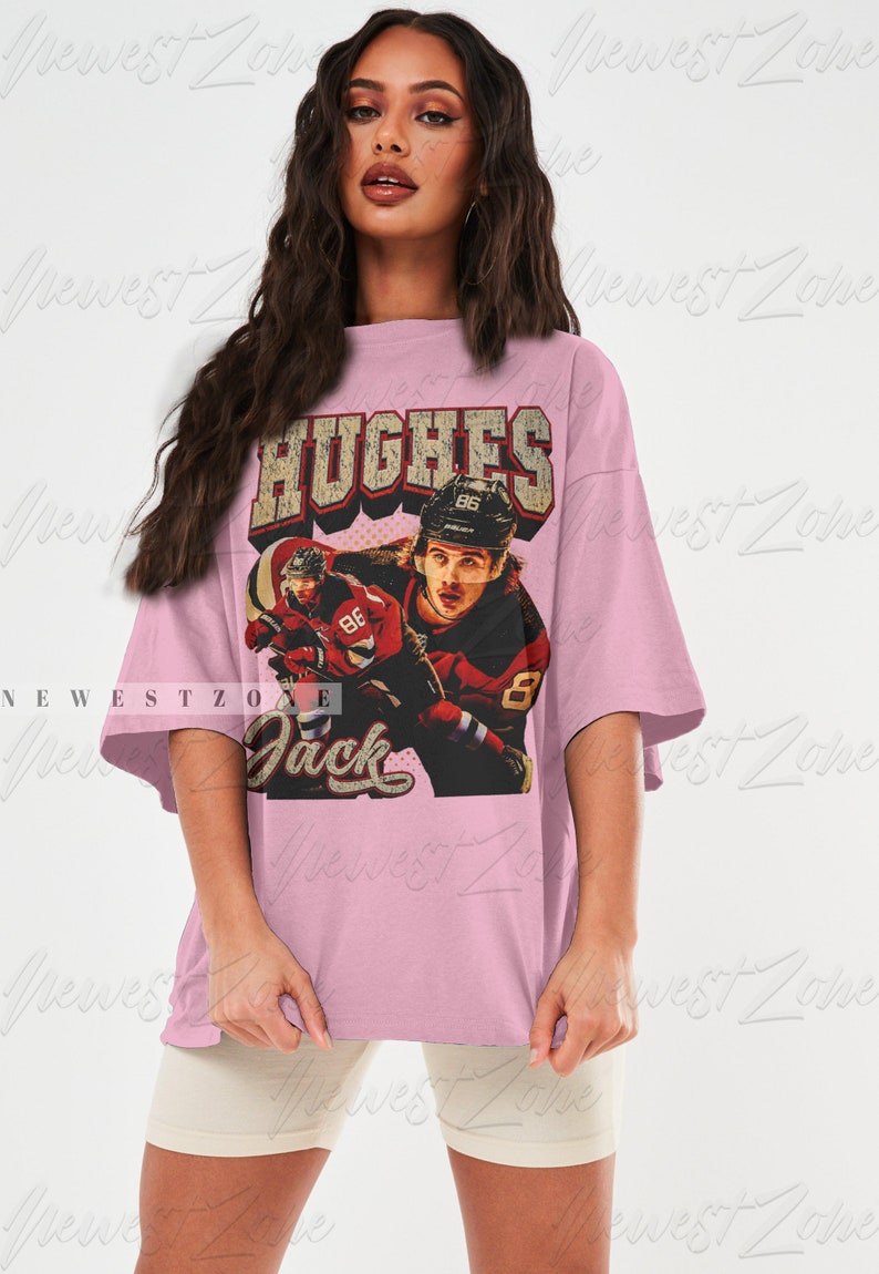 May include: A pink oversized t-shirt with a vintage-style graphic of a hockey player wearing a red and black jersey with the text "HUGHES" and "Jack" on the shirt.