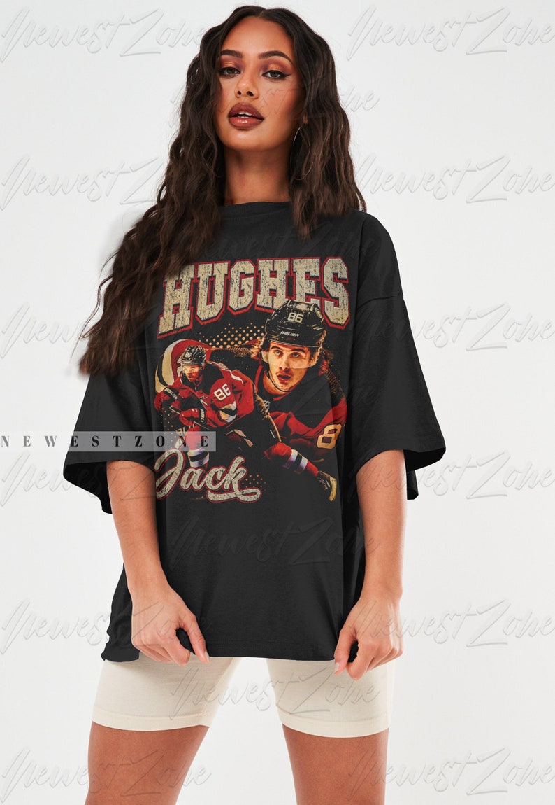 May include: Black oversized t-shirt with a vintage-style graphic of a hockey player wearing a red and white jersey with the text "HUGHES" and "Jack" on the front.