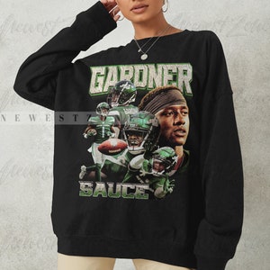 May include: Black sweatshirt with a graphic print of a football player wearing a green and white jersey with the text "GARDNER" and "SAUCE" on the front.