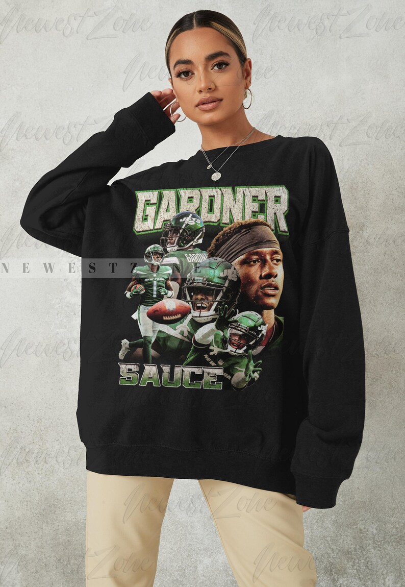 May include: Black sweatshirt with a graphic print of a football player wearing a green and white jersey with the text "GARDNER" and "SAUCE" on the front.