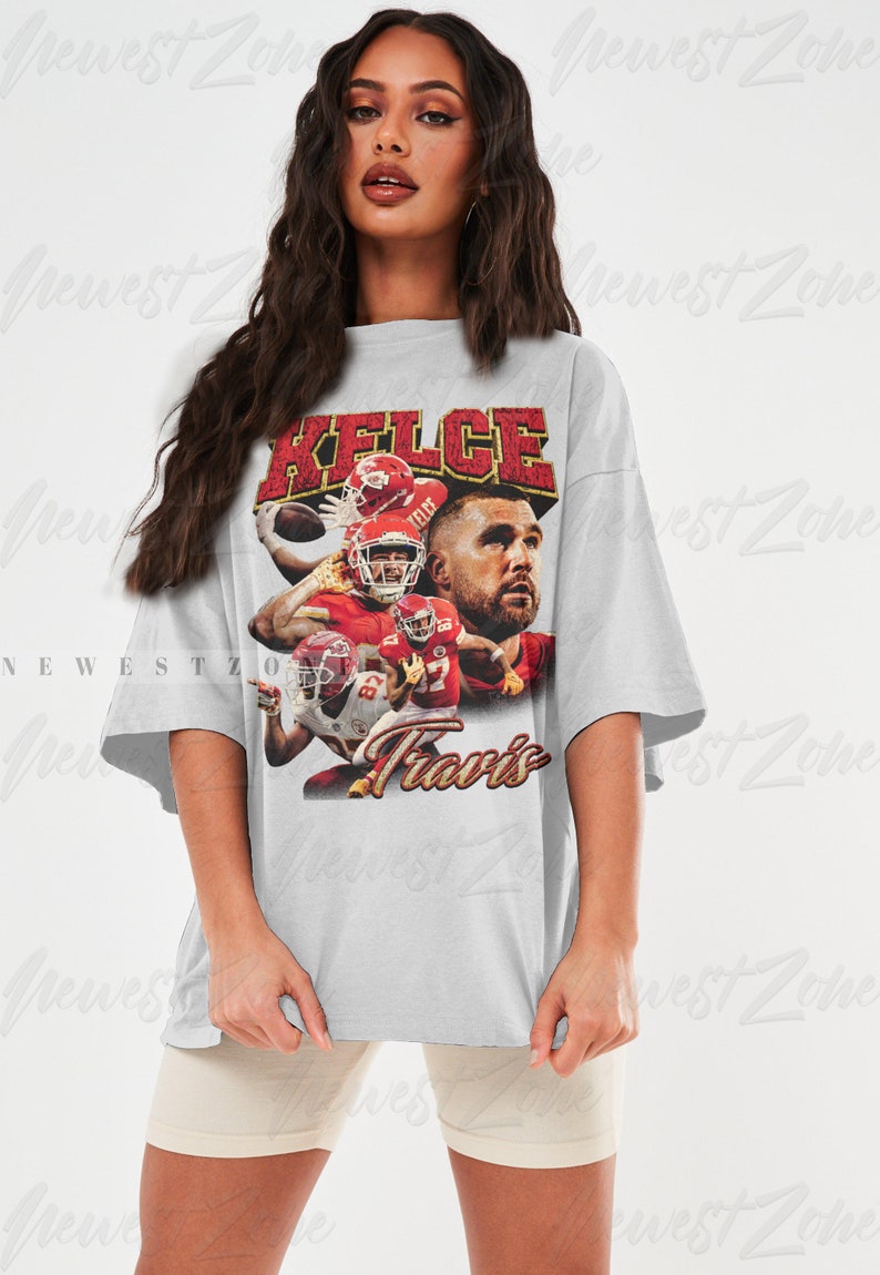 May include: A gray oversized t-shirt with a vintage-style graphic of a football player wearing a red and white jersey. The graphic includes the text "Kelce" and "Travis".