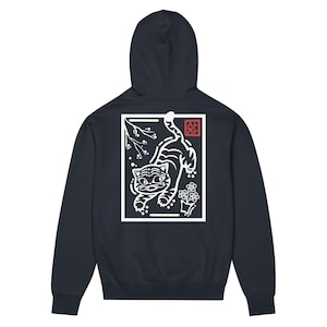 May include: Navy blue hoodie featuring a white graphic of a tiger, flowers, and branches within a rectangular frame. The design includes Japanese text in a red square. The hoodie has a hood and long sleeves.