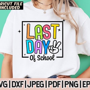 May include: A white t-shirt with a colorful graphic that says "Last Day of School" with a peace sign. The graphic is in a black rectangle with a white outline.