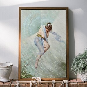 May include: A framed print of a classical painting depicting a woman in flowing blue fabric, with a light blue fan-like structure behind her. The artwork is set against a light background, framed in a brown wooden frame.