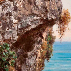 May include: A close-up of a rocky cliff face with a small amount of green foliage growing on the side. The cliff overhangs a body of blue water.