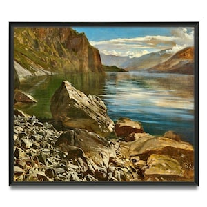 May include: A framed landscape painting depicting a calm lake surrounded by steep, rocky cliffs and mountains under a blue sky with white clouds. The foreground features a shoreline covered in dark gray stones and large, jagged brown boulders.