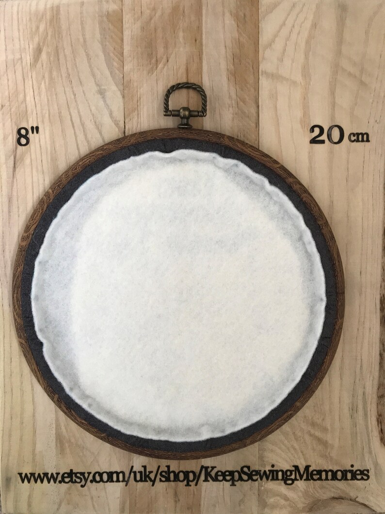 Puede incluir: Un aro de bordado de madera de 20 cm de di&aacute;metro con un inserto de fieltro blanco. El aro tiene un anillo de lat&oacute;n en la parte superior para colgarlo.