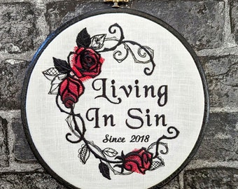 May include: Embroidered hoop art featuring a black and white floral design with red roses. The text reads "Living In Sin Since 2018".