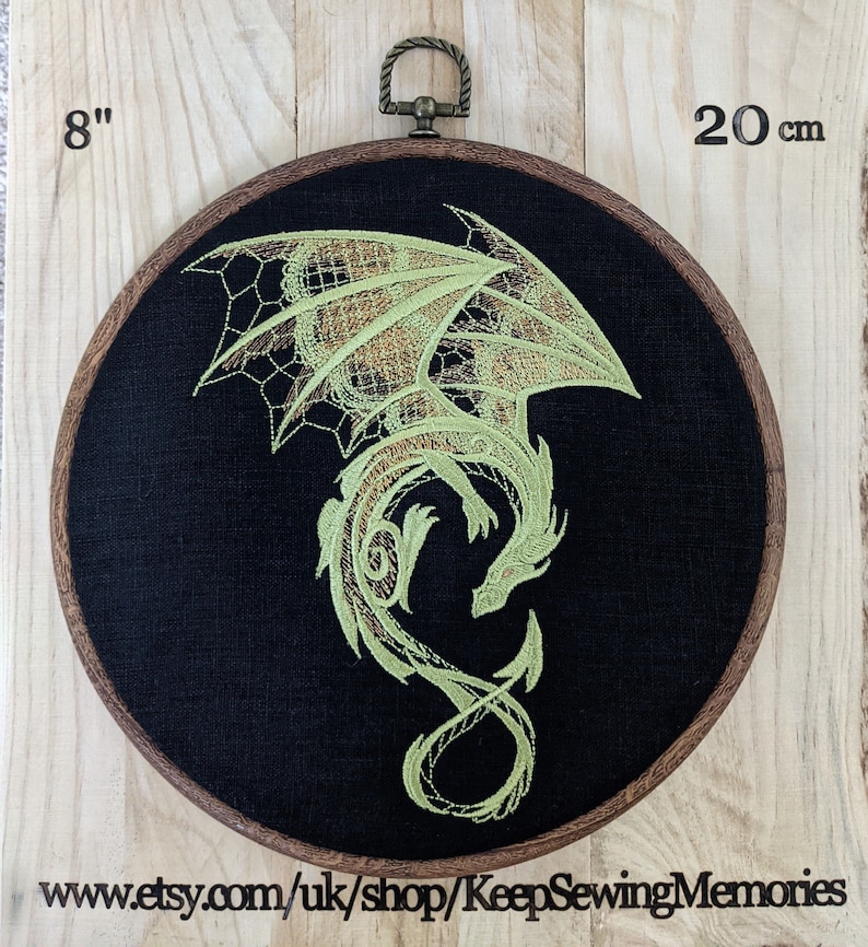 Puede incluir: Un aro de bordado de 20 cm de di&aacute;metro con un fondo de tela negro que presenta un dise&ntilde;o de drag&oacute;n verde. El drag&oacute;n est&aacute; enroscado con las alas extendidas. El aro est&aacute; hecho de madera y tiene un anillo de lat&oacute;n.