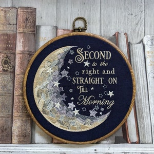 May include: Embroidered hoop art with a navy blue background featuring a crescent moon with stars and the text "SECOND to the right and STRAIGHT ON Till Morning".