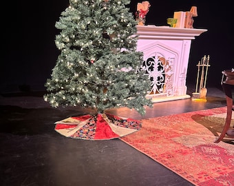 May include: A decorated Christmas tree with a red and gold tree skirt, standing in front of a white fireplace with a wrought iron screen.
