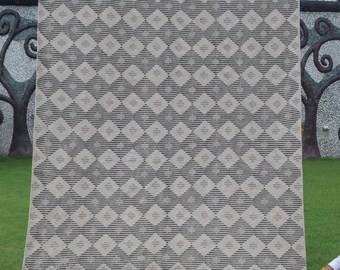 Puede incluir: Una alfombra blanca y negra con flecos en los bordes. La alfombra tiene un patrón de diamantes con líneas negras.