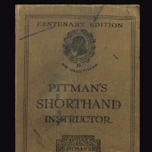 Puede incluir: Un libro marrón con el título "PITMAN'S SHORTHAND INSTRUCTOR" en letras negras. El libro es una edición centenaria y presenta un retrato de Sir Isaac Pitman.