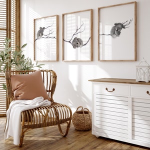 a set of three digital prints featuring a gum tree branched spanned across the three prints with a baby koala sleeping on the branch in each print. Perfect for any room but great for creating a peaceful, serene environment in a baby nursery.