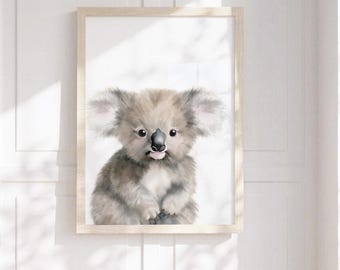 May include: A framed wall art print featuring a watercolor-style illustration of a fluffy koala with large ears, dark eyes, and a black nose. The koala is depicted in shades of gray and white, centered within a light-colored wooden frame.