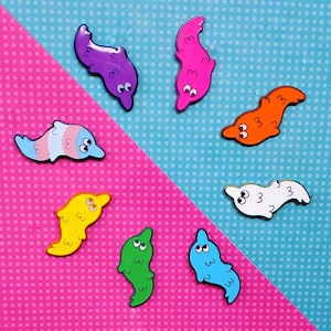 May include: Nine colorful enamel pins shaped like worms with different expressions. The pins are on a blue and pink polka dot background.