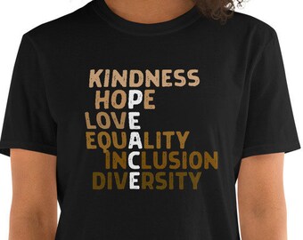 May include: Black t-shirt with the words "KINDNESS", "HOPE", "LOVE", "EQUALITY", "INCLUSION", and "DIVERSITY" arranged in a vertical column, with the letters "PEACE" spelled out diagonally across the words.