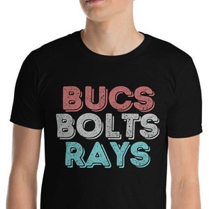 Puede incluir: Una camiseta negra con las palabras "BUCS BOLTS RAYS" en una fuente de estilo retro. Las palabras están en diferentes colores: rojo, naranja y azul.