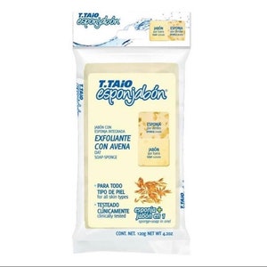 May include: A white package with blue text and a yellow bar of soap inside. The soap is labeled "T.TAIO esponjabón" and is described as an exfoliating soap with oat. The package also says "sponge + jabón en 1" which means "sponge + soap in 1".