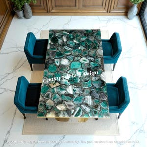 Puede incluir: Una mesa rectangular con una tapa de piedra de ágata verde y gris, rodeada de cuatro sillones color turquesa. La mesa tiene una base dorada. El texto "Epoxy Arts Design" es visible en la superficie de la mesa.