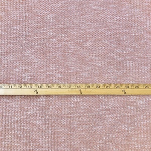May include: A close-up of a light brown waffle knit fabric with a white ruler measuring 25 inches.