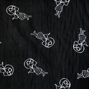 May include: Black fabric with a white repeating pattern of a stylized person wearing glasses and a dress. The person is depicted with arms outstretched and a smile.