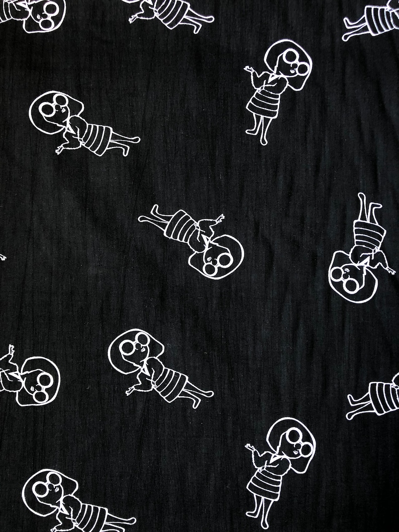 May include: Black fabric with a white repeating pattern of a stylized person wearing glasses and a dress. The person is depicted with arms outstretched and a smile.