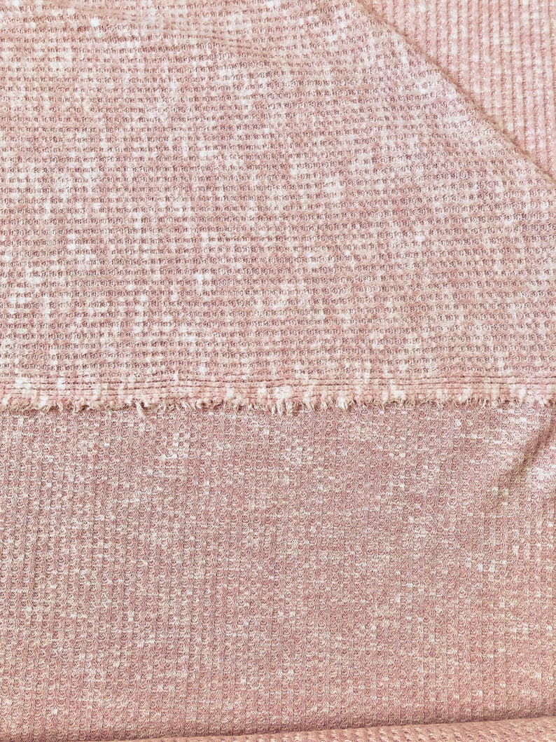 May include: A close-up of a pink waffle knit fabric with a textured surface.