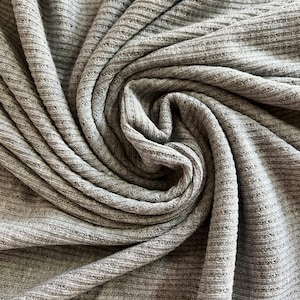 May include: Close-up of a gray ribbed fabric, folded and twisted into a spiral shape.