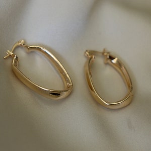 May include: A pair of gold oval hoop earrings. The earrings are simple and elegant, with a smooth, polished finish.