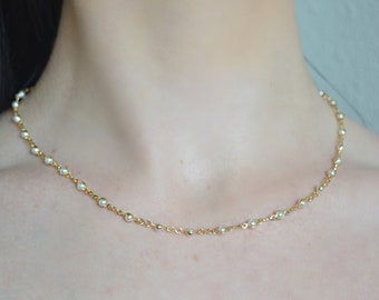 May include: A delicate gold chain necklace with small white pearls. The necklace is simple and elegant, perfect for everyday wear.