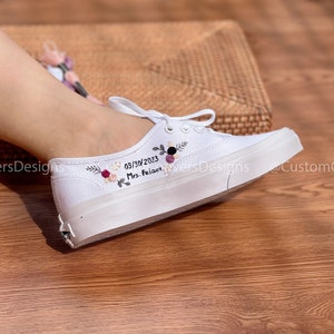 May include: White canvas shoes with embroidered flowers and the text "03/30/2023 Mrs. Palace" on the side.