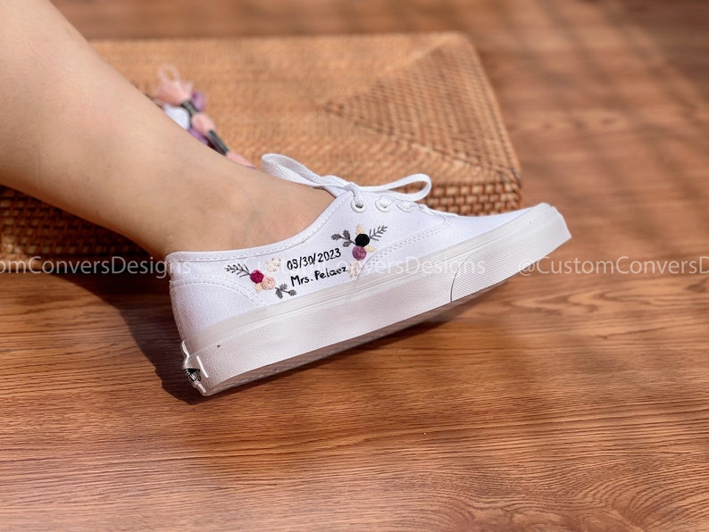 May include: White canvas shoes with embroidered flowers and the text "03/30/2023 Mrs. Palace" on the side.
