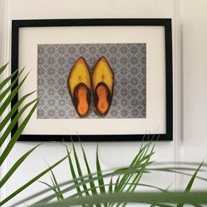 Puede incluir: Una impresión enmarcada de dos zapatillas de cuero amarillo con ribetes negros sobre un fondo estampado.