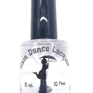 May include: A clear glass bottle of nail polish with a black cap. The bottle has a black and white label that says "Rain Dance Lacquer" and features a silhouette of a girl holding an umbrella. The label also says "15 mL" and "10 Free".