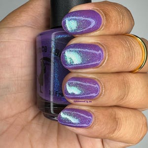 May include: Purple nail polish with a holographic shimmer finish. The bottle is labeled "Dance With The Devil" and "10 Free".