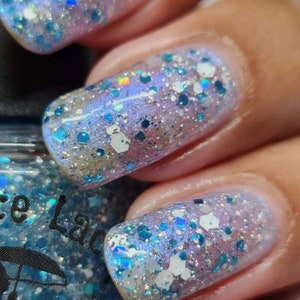 May include: Close-up of fingernails painted with a light blue nail polish with iridescent glitter. The glitter is a mix of white, blue, and silver.