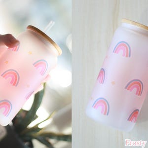 May include: A frosted glass water bottle with a pink and white rainbow pattern and a bamboo lid. The bottle has a straw and the text "Frosty Rainbow" is printed on the bottom.