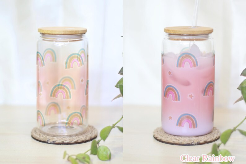 May include: Two glass jars with bamboo lids and rainbow designs. The jar on the left is empty, while the jar on the right is filled with a pink liquid. Both jars are sitting on a woven coaster. The text "Clear Rainbow" is visible at the bottom of the image.