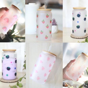 May include: Six frosted glass tumblers with bamboo lids and straws. The tumblers feature different patterns: strawberries, black cats, rainbows, and flowers.