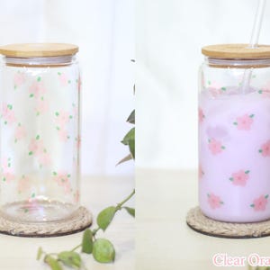 May include: A clear glass jar with a bamboo lid and a floral pattern. The jar is filled with a light purple liquid and has a straw in it. The jar is sitting on a rope coaster. The text "Clear Orange Floral" is visible at the bottom of the image.