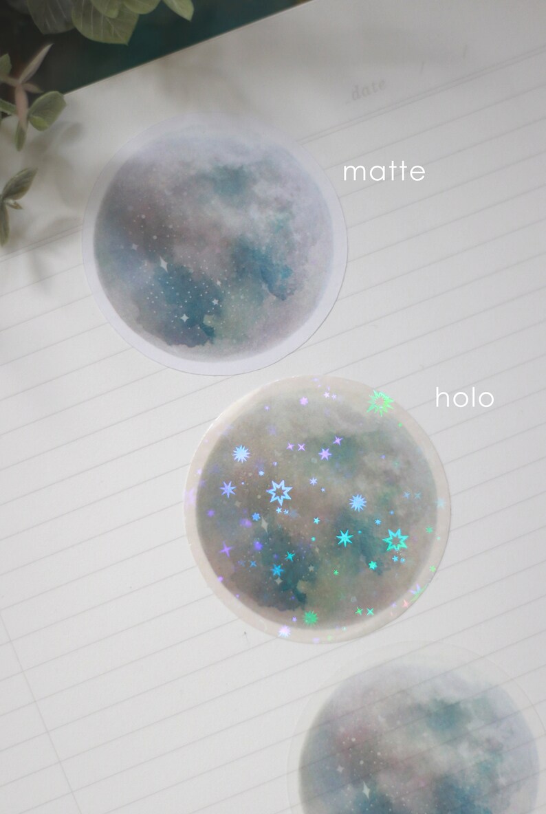Puede incluir: Dos pegatinas redondas con un dise&ntilde;o de luna de acuarela. La pegatina superior es mate y la pegatina inferior es hologr&aacute;fica con estrellas iridiscentes.