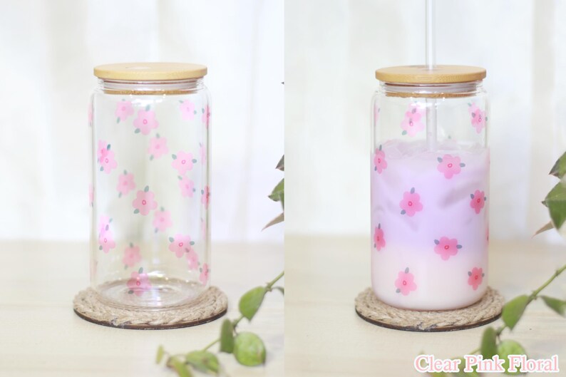 May include: Clear glass jar with a pink floral pattern and a wooden lid. The jar is filled with a light purple liquid and has a straw.