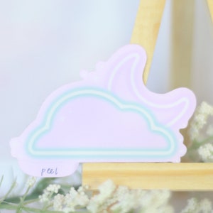 May include: A pastel purple cloud sticker with a crescent moon outline. The sticker has a light blue outline and the word "peel" written on the bottom.